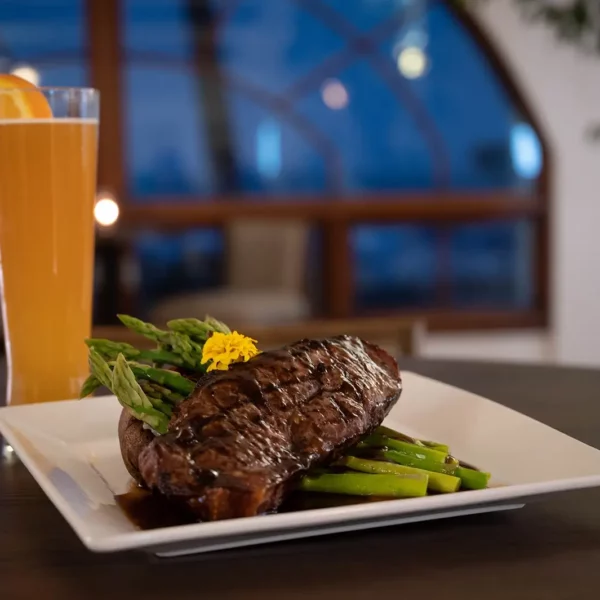 plated steak with a glass of beer in the background at beautiful oceanfront Plaza Resort & Spa in Daytona Beach Florida