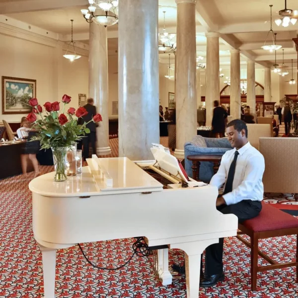 young black man wearing a white shirt and tie playing the piano at beautiful oceanfront Plaza Resort & Spa in Daytona Beach Florida