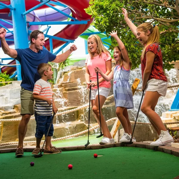 man and woman family with three young children playing mini golf