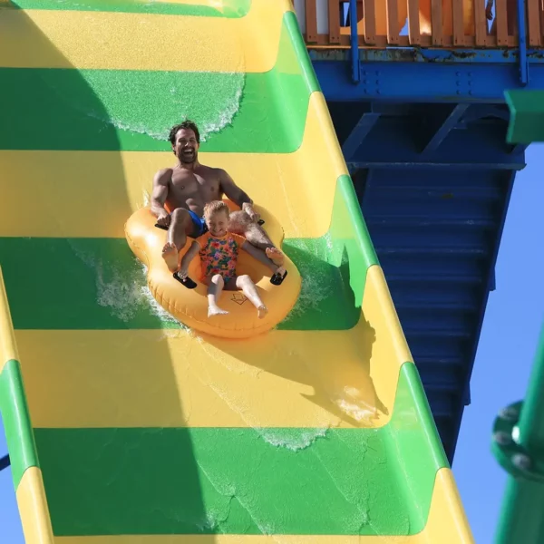father and young daughter going down a water park slide on a tube