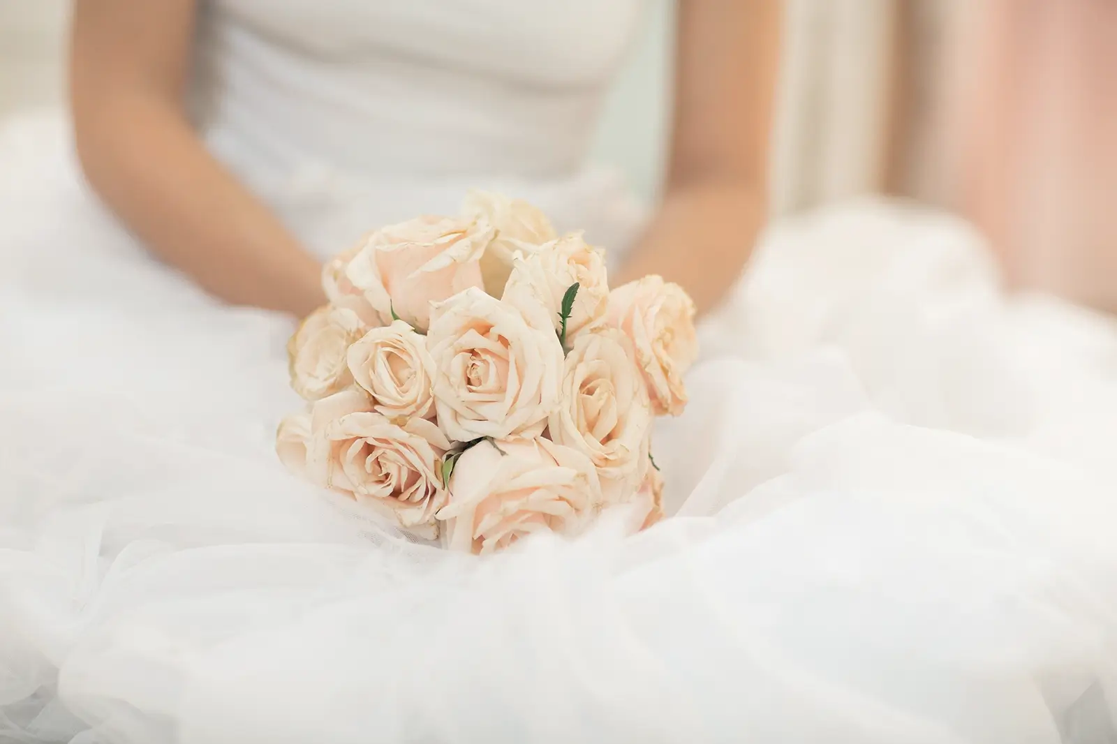 close up of a bridal bouquet with bride in wedding gown behind