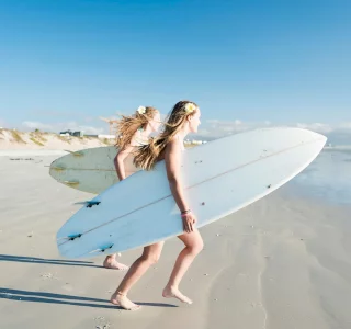 two young girls heading out to the ocean with surfboards